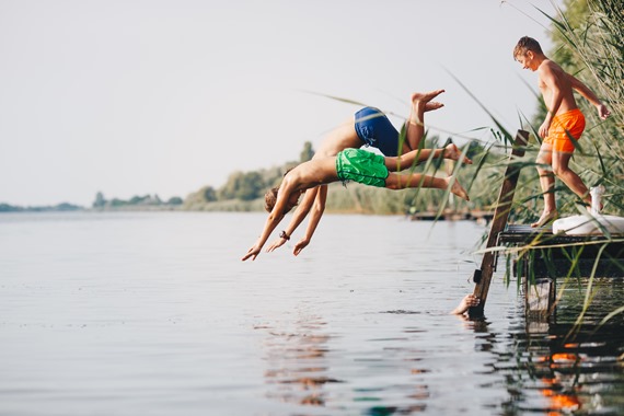 Billede af tre drange, der hopper i vandet fra en badebro
