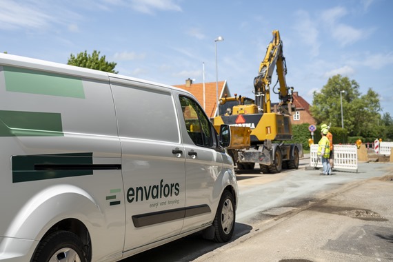 Hvid varevogn med Envfors-logo og gravearbejde med afspærring og en gravko i baggrunden
