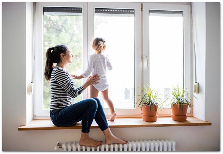 Mor med lille pige sidder i vindueskarm